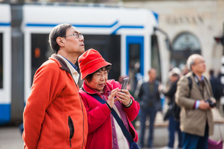 Asian tourists using their cellphones to take pictures at Dam Square in Amsterdamのeditorial素材