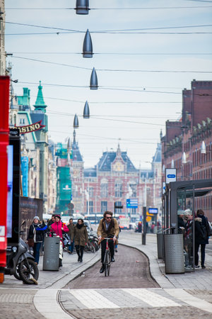 Cyclist in a cold early spring day at the Old Central district of Amsterdamのeditorial素材