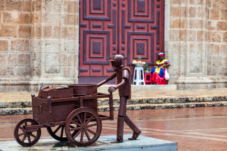 Sculpture of a man with a traditional wheelbarrow at the San Pedro Claver square in Cartagena de Indiasのeditorial素材