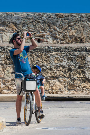 Father and his baby riding on a bike rental around the city in Cartagena de Indiasのeditorial素材