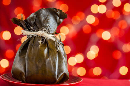 Traditional Colombian tamale as made on Tolima region over a christmas red backgroundの写真素材