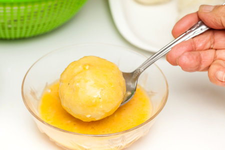 Preparation steps of traditional Colombian dish called stuffed potatoes: Dunking stuffed potatoes in egg and flour mixtureの写真素材