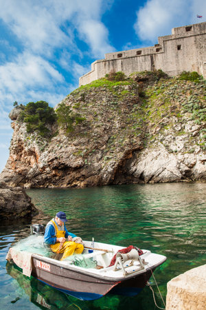 Fisherman at Dubrovnik West Pier and the medieval Fort Lovrijenac located on the western wall of the cityのeditorial素材