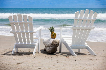 Empty white wooden chairs at a paradisiac beach on the tropics in a beautiful sunny day