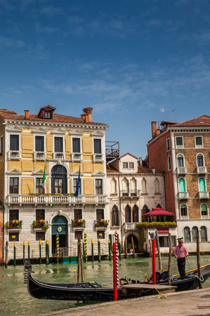 Gondolier enlisting his gondola at a beautiful canal in Venice on a sunny early spring dayのeditorial素材