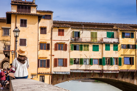 Young female tourists at Ponte Vecchio a medieval stone closed-spandrel segmental arch bridge over the Arno River in Florenceのeditorial素材