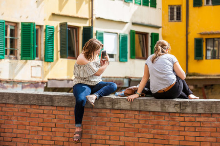Two young tourists girls at Ponte Vecchio to medieval stone closed-spandrel segmental arch bridge over the Arno River in Florenceのeditorial素材