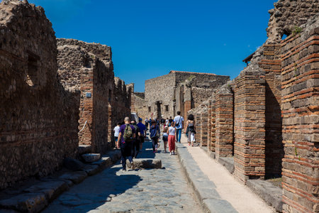Tourists at the streets of Pompeii made of large blocks of black volcanic rocksのeditorial素材