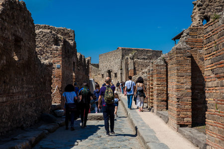 Tourists at the streets of Pompeii made of large blocks of black volcanic rocksのeditorial素材