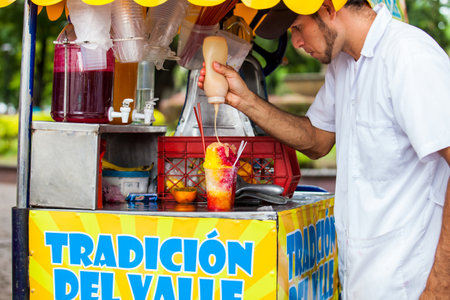 CALI, COLOMBIA - OCTOBER, 2019: Street vendor in the city of Cali in Colombia preparing and selling a traditional sweet water ice called choladoのeditorial素材