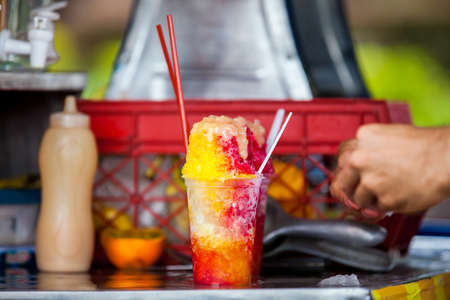 Street vendor in the city of Cali in Colombia preparing and selling a traditional sweet water ice called choladoの写真素材