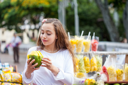 Beautiful young girl at Paseo Bolivar Square in the city of Cali eating tropical fruits in Colombia