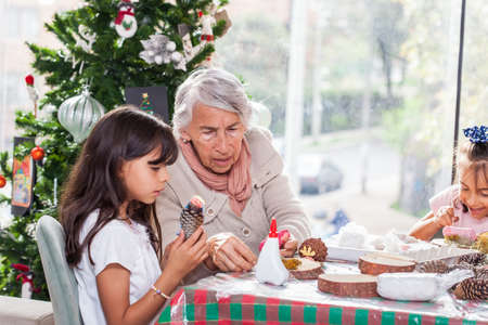 Grandmother teaching her granddaughters how to make christmas Nativity crafts - Real familyの写真素材
