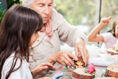 Little girl having fun with her sister and their grandmother while making christmas Nativity crafts - Real familyの写真素材