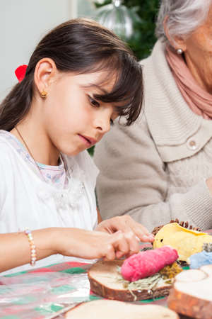 Little girl having fun while making christmas Nativity crafts with her grandmother - Real familyの写真素材