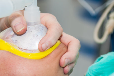 Closeup of an anesthetist at a operating room holding an oxygen mask on patient face
