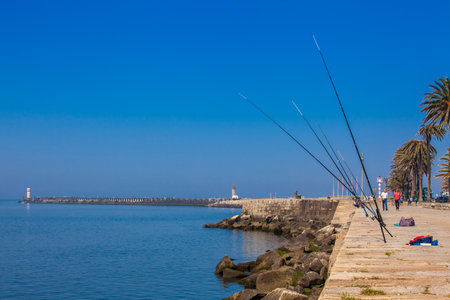 PORTO, PORTUGAL - MAY, 2018:  Fishing poles in a sunny early spring day at the beautiful promenade along the Porto coast near the Douro river mouthのeditorial素材