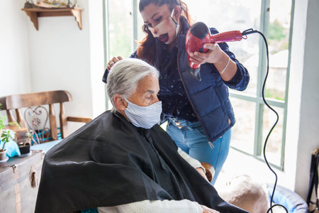 Senior woman getting a haircut at home during Covid-19 pandemic wearing face mask