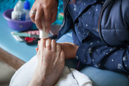 Close up of a senior woman foot while getting a pedicure at home during Covid-19 pandemicの写真素材