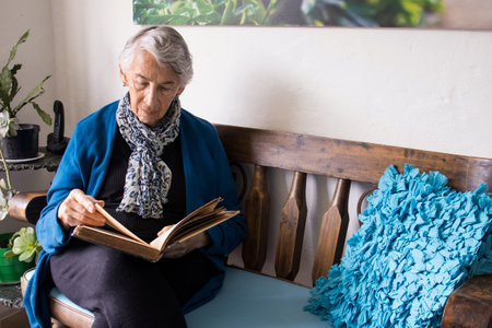 Senior woman alone at home reading an old book
