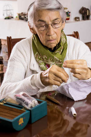 Senior woman sewing a homemade face mask during the Covid-19 pandemicの写真素材