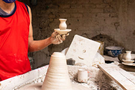 Man making ceramic articles on the potters wheel in a traditional factory in the city of RÃ¡quira located in the department of Cundinamarca in Colombiaの写真素材