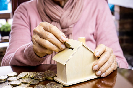 Closeup of a hand of a senior woman sitting at her home saving money