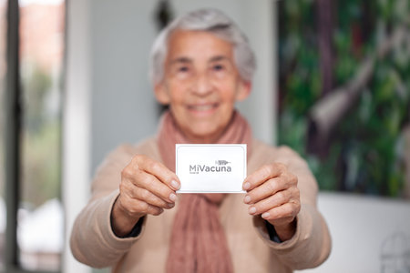 Senior woman at her home holding her vaccination certificate after getting the Covid-19 vaccine in...