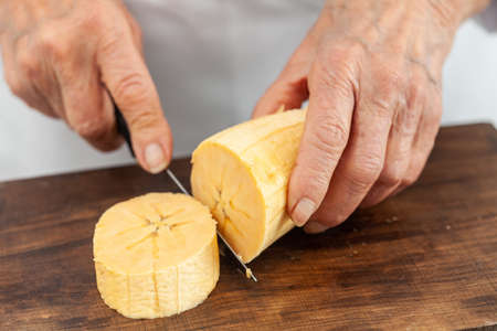 Closeup of a senior woman hands while cuts a ripe plantainの写真素材