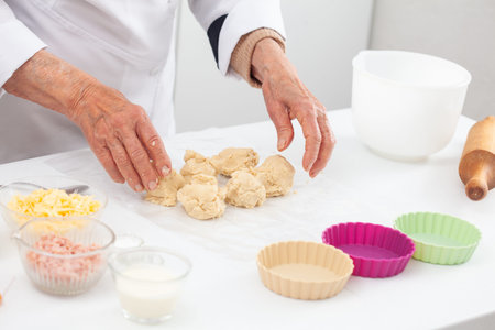 Senior woman preparing dough for a delicious cheese and ham tartlet