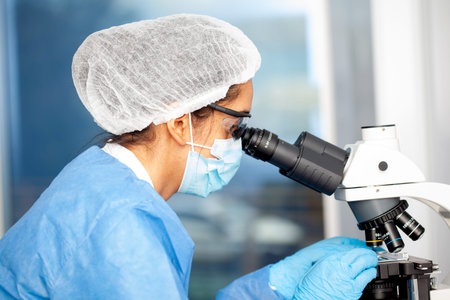 Young female scientist looking at samples under the microscope