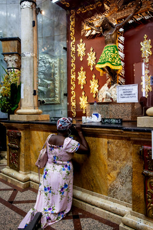BUGA, COLOMBIA - OCTOBER 2021. Kneeling woman praying in front of the sacred image of the Lord of Miracles at Minor Basilica of the Lord of Miracles located in in the Historic Center of the city of Guadalajara de Buga in Colombiaのeditorial素材
