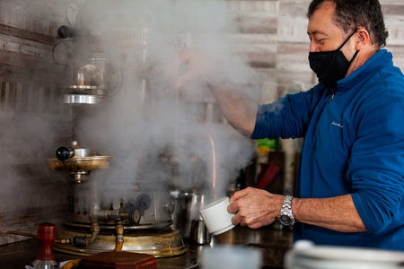 SALENTO, COLOMBIA - JULY 2021. One of the owners of the famous Cafe de la Esquina, in the small city of Salento in Colombia, steaming a cup with the oldest coffee maker on town built on 1905のeditorial素材