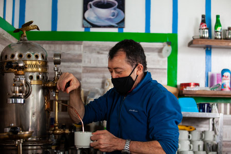 SALENTO, COLOMBIA - JULY 2021. One of the owners of the famous Cafe de la Esquina, in the small city of Salento in Colombia, preparing a cup of coffee with the oldest coffee maker on town built on 1905のeditorial素材