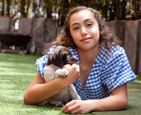 Beautiful young girl having fun with her small French Braque puppies