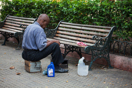CARTAGENA DE INDIAS, COLOMBIA - AUGUST, 2011: Street shoe polisher sit lonely waiting for clients at the Bolivar park in the walled city in Cartagena de Indiasのeditorial素材
