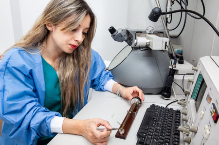 Young female scientist loading a grid with a specimen on the sample holder of a transmission...