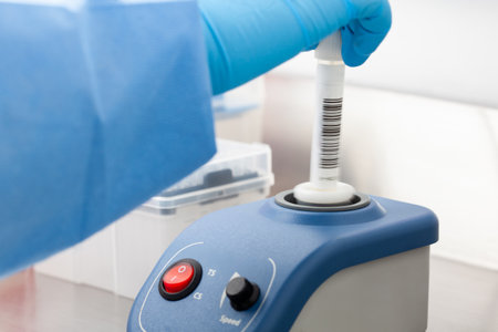 Scientist mixes a biological sample for analysis using a lab vortex mixer with adjustable stirring speed with touch.の写真素材