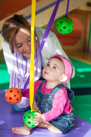Beautiful 10 month old baby girl playing with her mom. Early stimulation for toddlers concept.の写真素材