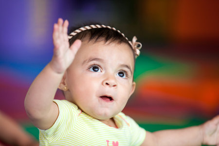 Portrait of a happy beautiful ten months baby girl on a colorful background. Early stimulation for toddlers concept.の写真素材