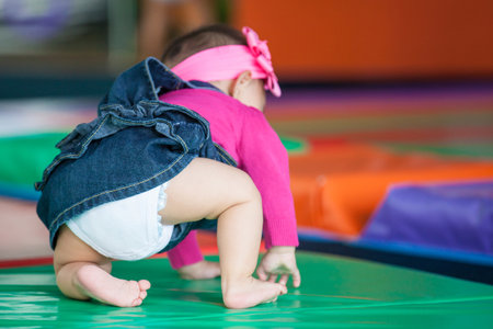 Beautiful ten months baby girl crawling on a colorful background. Early stimulation for toddlers concept.の写真素材