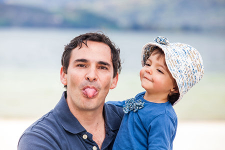 Young father having fun with his baby girl at the beautiful white beach of Lake Tota located in the...