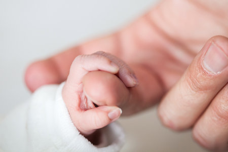 Closeup of a newborn hand and her father finger at hospital on the day of her birth. fatherhood conceptの写真素材