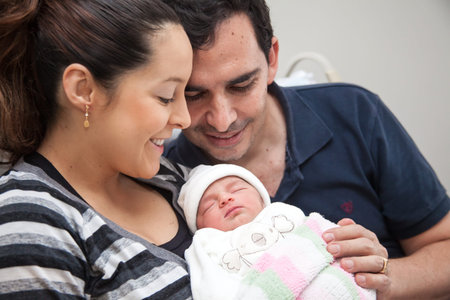 Young mother and father with their newborn baby girl at the hospital on the day of her birth. Family...