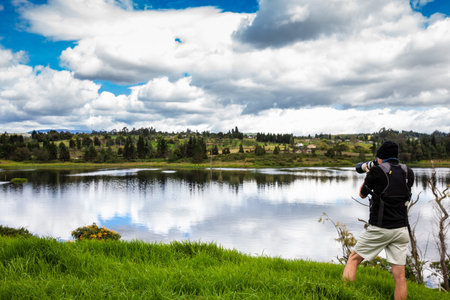 Male tourist taking photos at an artificial lake in the region of Boyaca in Colombia. La Playa reservoir located at the Tuta Municipality in Boyaca.の写真素材