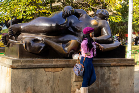 MEDELLIN, COLOMBIA - JANUARY 17, 2024: Tourist visiting the bronze sculptures made by the famous Colombian artist Fernando Botero in Medellin. Reclining Woman.のeditorial素材