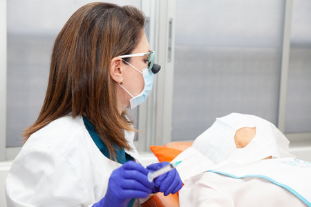 Dermatologist carrying out a skin biopsy on the face of a senior adult patient. Application of anesthesia.の写真素材
