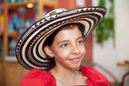 Sweet teenager girl in Cartagena de Indias wearing a traditional sombrero vueltiao. Travel concept. Sitting alone. Happy girl.の写真素材