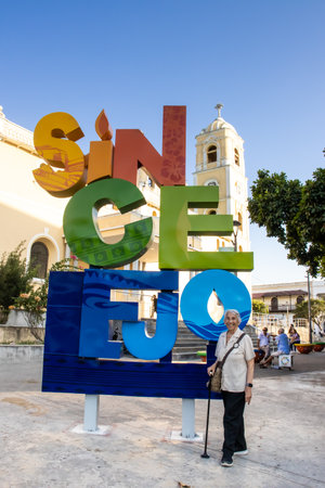 Sincelejo, Colombia - 22 January 2024. Senior woman at the Sincelejo sign next to the San Francisco de Asis Cathedral located in Santander Square.のeditorial素材