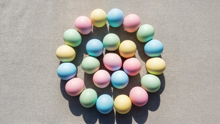 Pastel easter eggs in concentric circles. Geometric spring holiday layout on grey linen fabric background with shadows.の素材